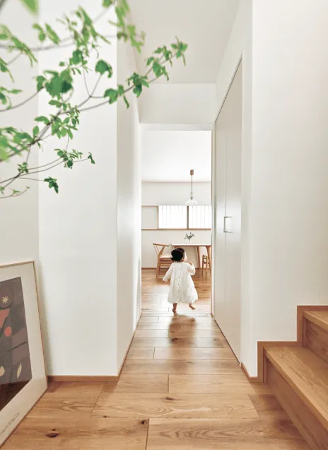 明るい木の廊下を歩く小さな子供。家の中には自然の要素が取り入れられ、住友林業の家ならではの温かみのあるデザイン。